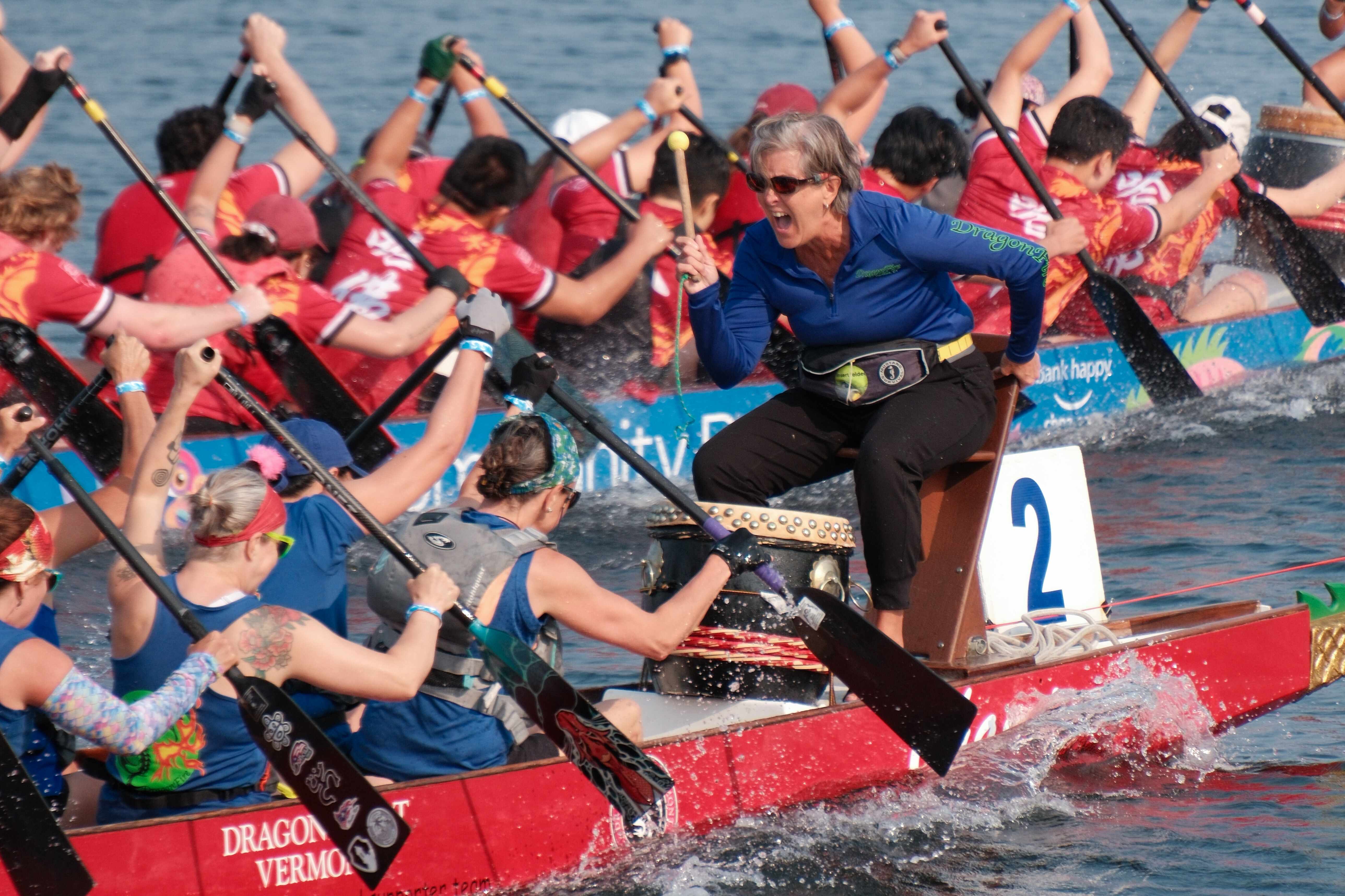 Dragon boat racers paddling energetically on the water during a competitive event.