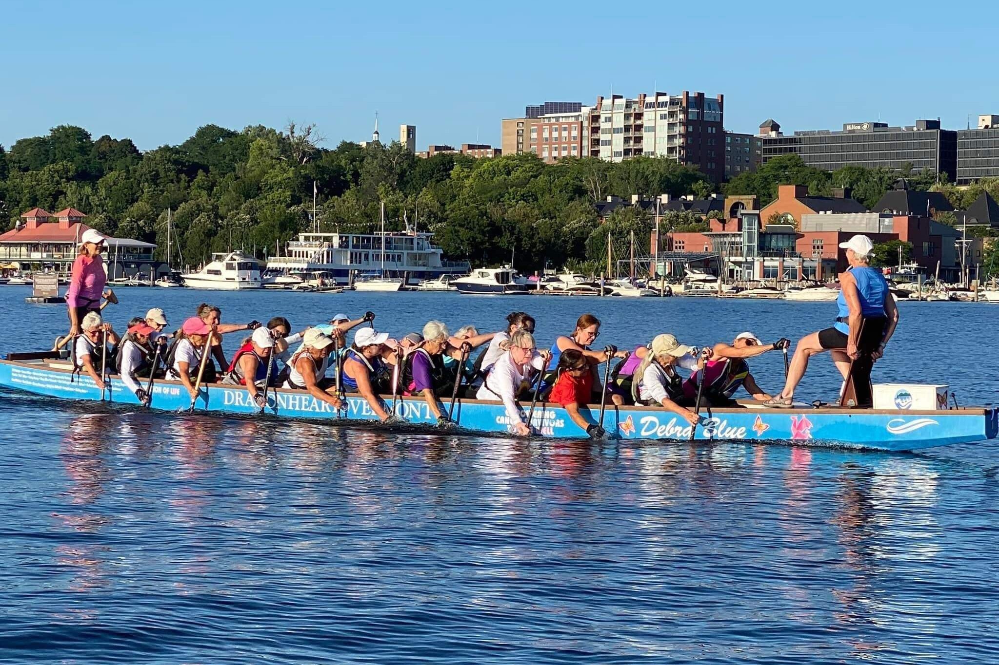 A group of women paddling together in a dragon boat on a sunny day.