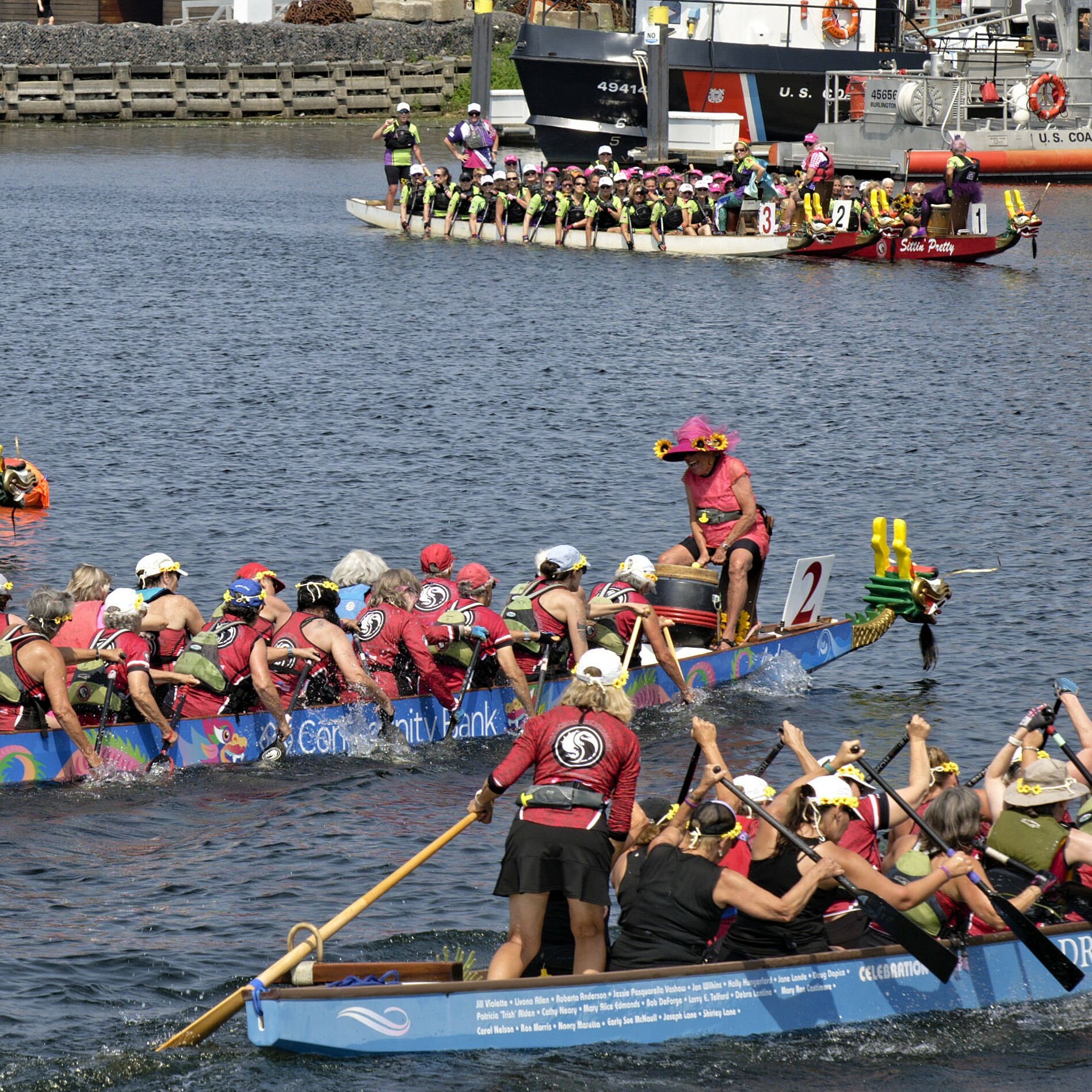Teams compete in a dragon boat race on a sunny day.